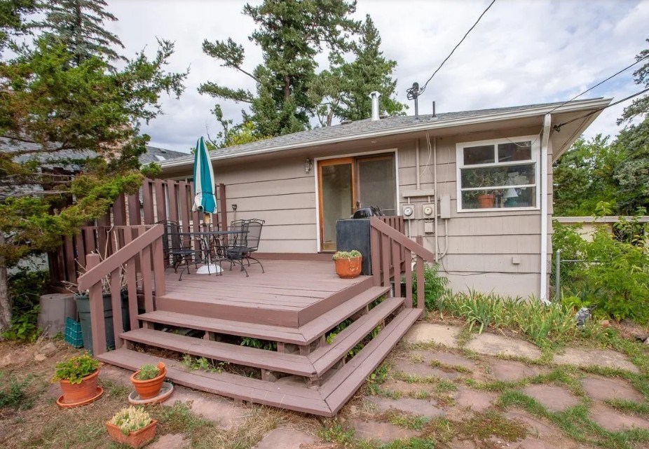 A house with a brown deck and a green umbrella.